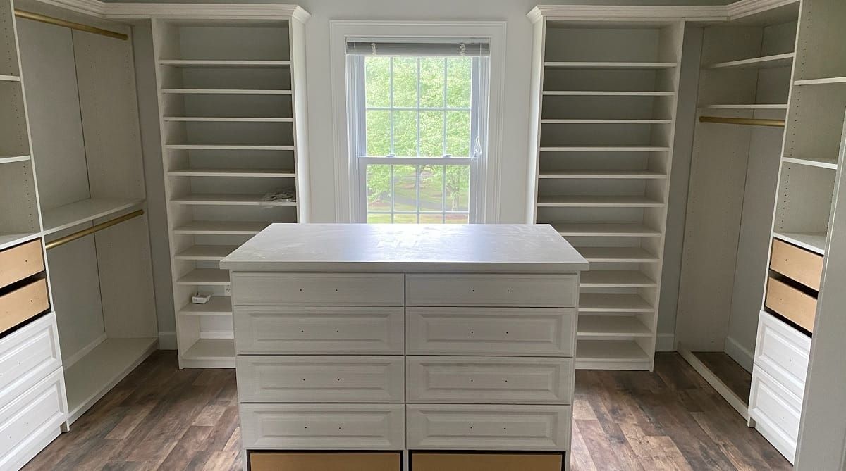 Custom walk-in closet with built-in shelving, hanging rods, drawers, and a central storage island.