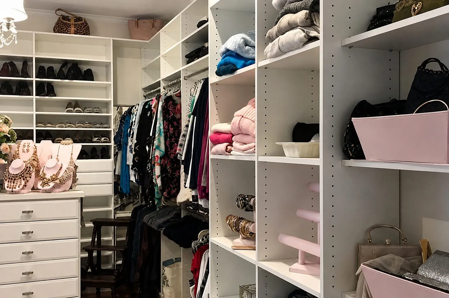 Luxury custom closet featuring organized shoe shelves, clothing racks, drawers, folded garments, and handbag storage.