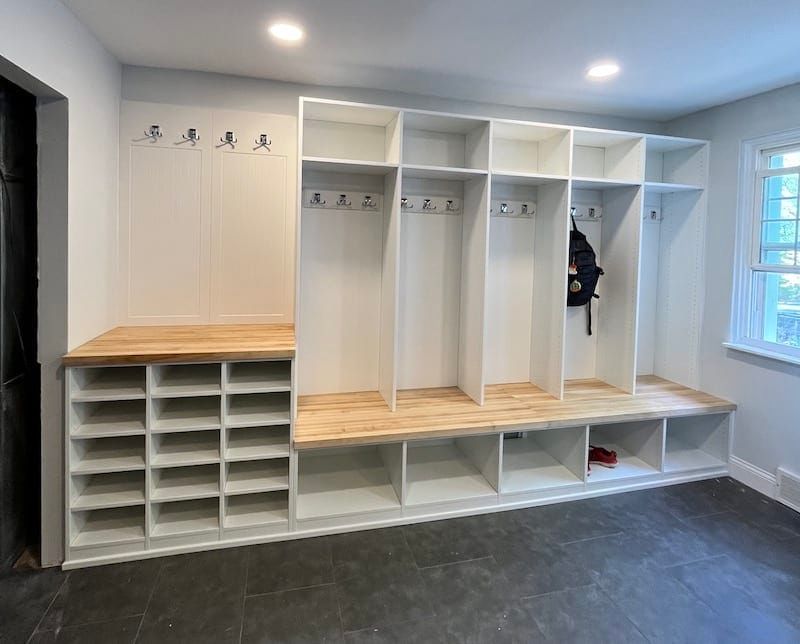 Custom mudroom storage with white cubbies, hooks, and wooden bench tops for organized entryway storage.