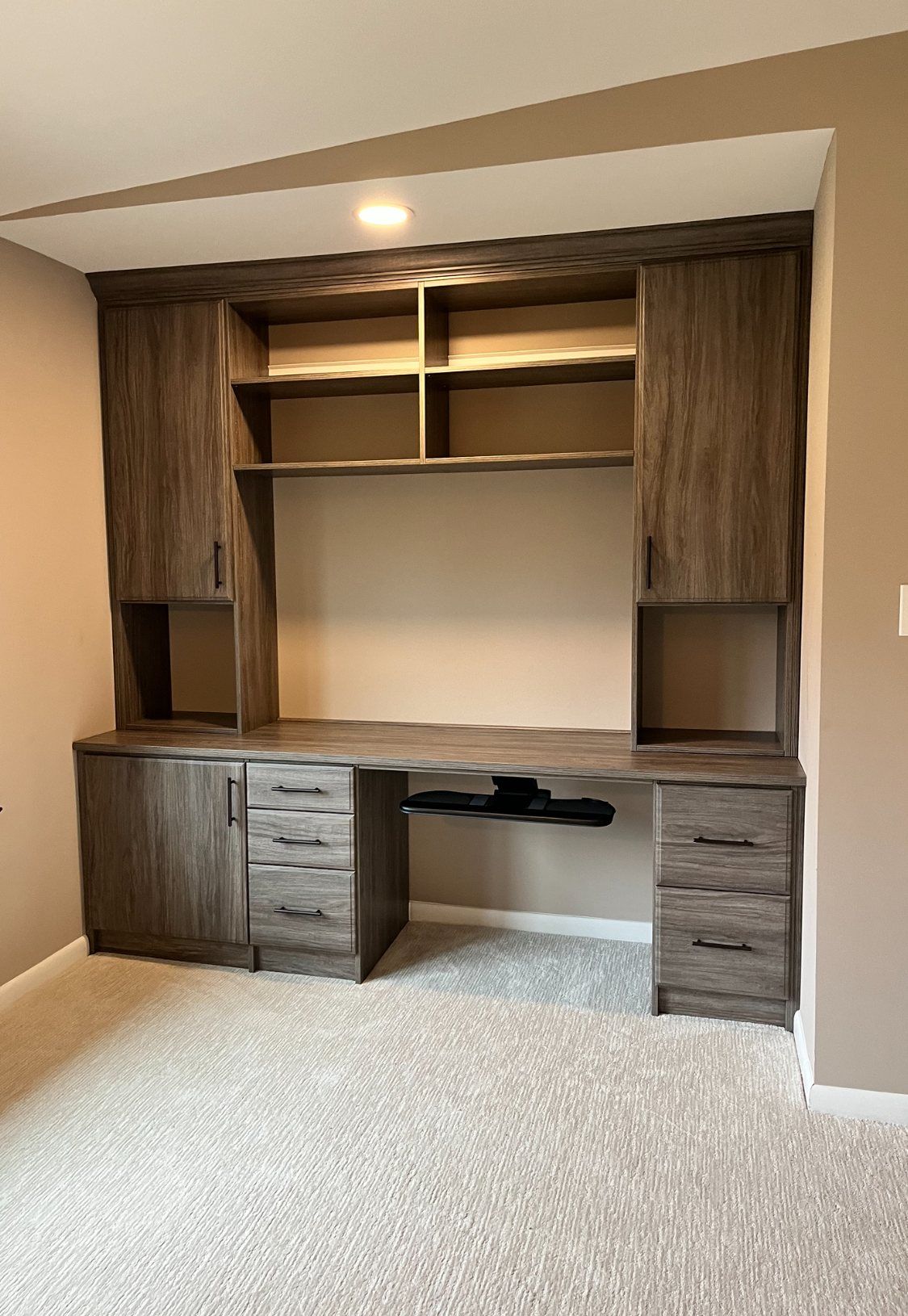 Home office with a wood-grain built-in desk, open shelves and upper cabinets