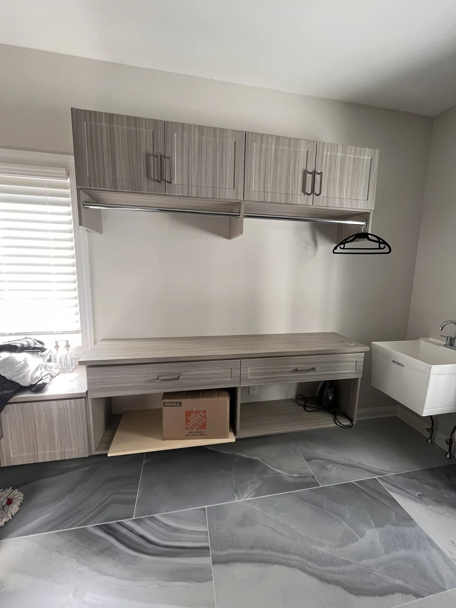 Laundry and mudroom wall with upper cabinets, a hanging rod and a folding counter with drawers