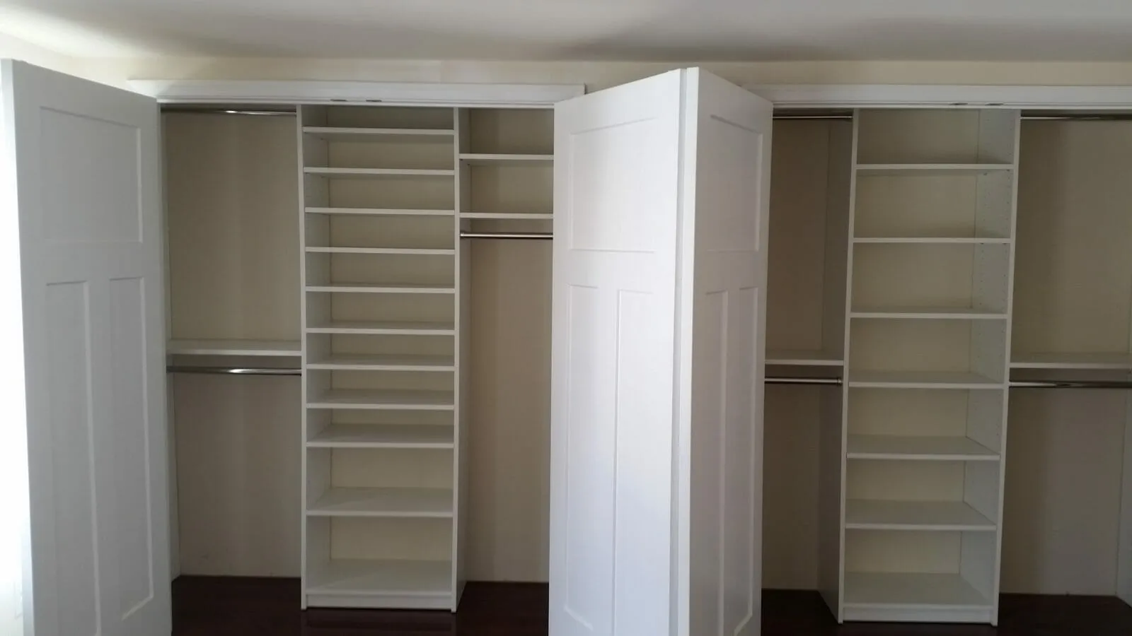 Dual white reach-in closets with central shelving and hanging rods for organized home storage solutions