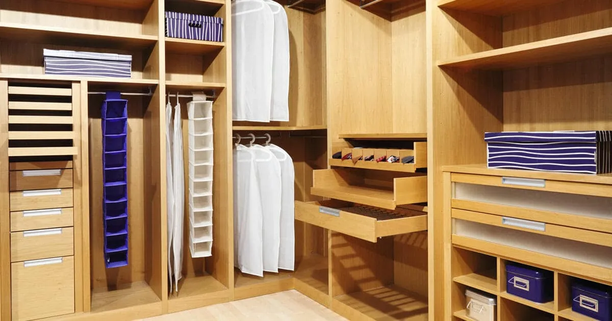 Custom walk-in closet with light wood cabinetry, built-in drawers, shelving, hanging rods, and organized storage compartments.