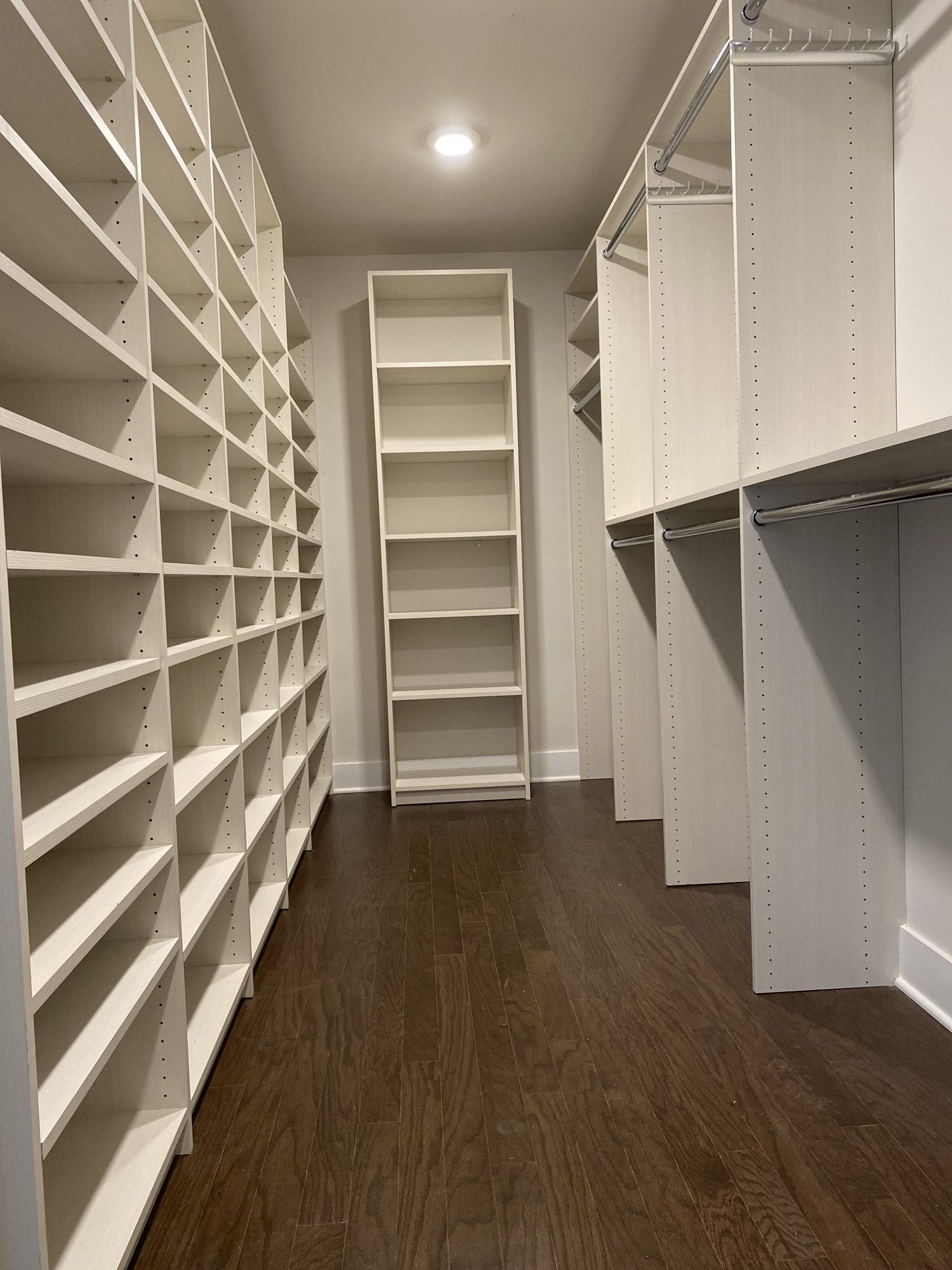 Long custom walk-in closet with floor-to-ceiling shelving and double-hang rods