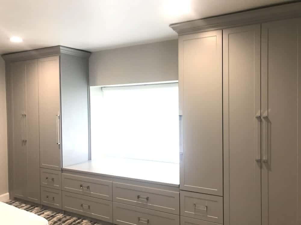 Gray wardrobe towers on both sides of a window seat