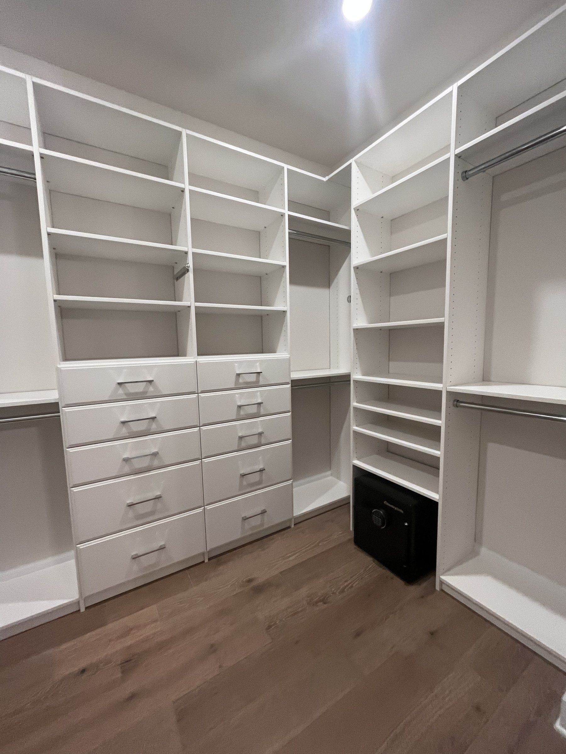 White walk-in closet with corner shelving, drawers and a shoe wall