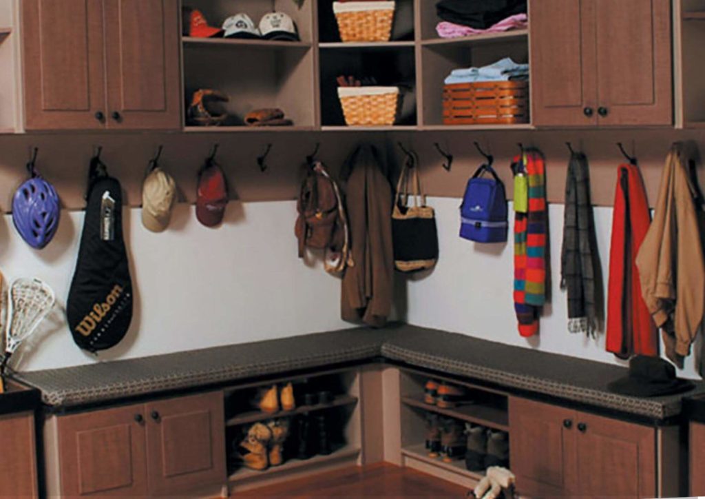dark wood mudroom storage with open shelving for shoes and may hooks for sports equipment