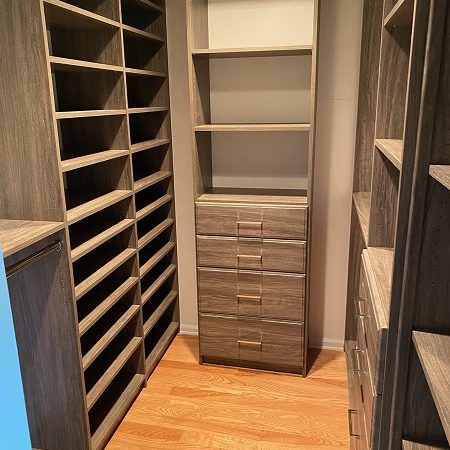 customized walk-in closet storage with coffee brown shelving and drawers in narrow closet